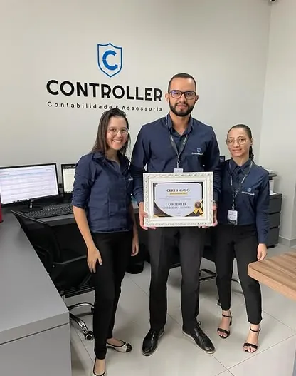 Vitor Rodrigues Dias e duas pessoas da equipe, de camisa da Controller, segurando o certificado de 2024 no escritório.